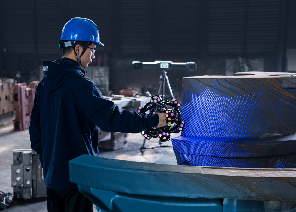 Operator scanning a large industrial workpiece with blue laser lines